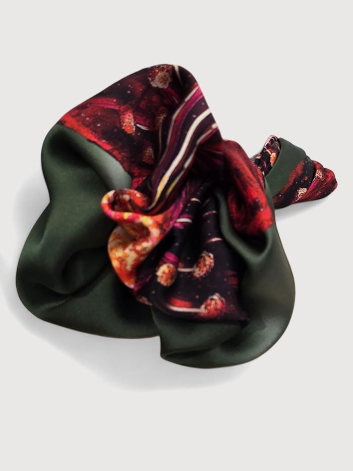 Pañuelo de seda de color verde oscuro con estampado de detalles en rojo, naranja y blanco.