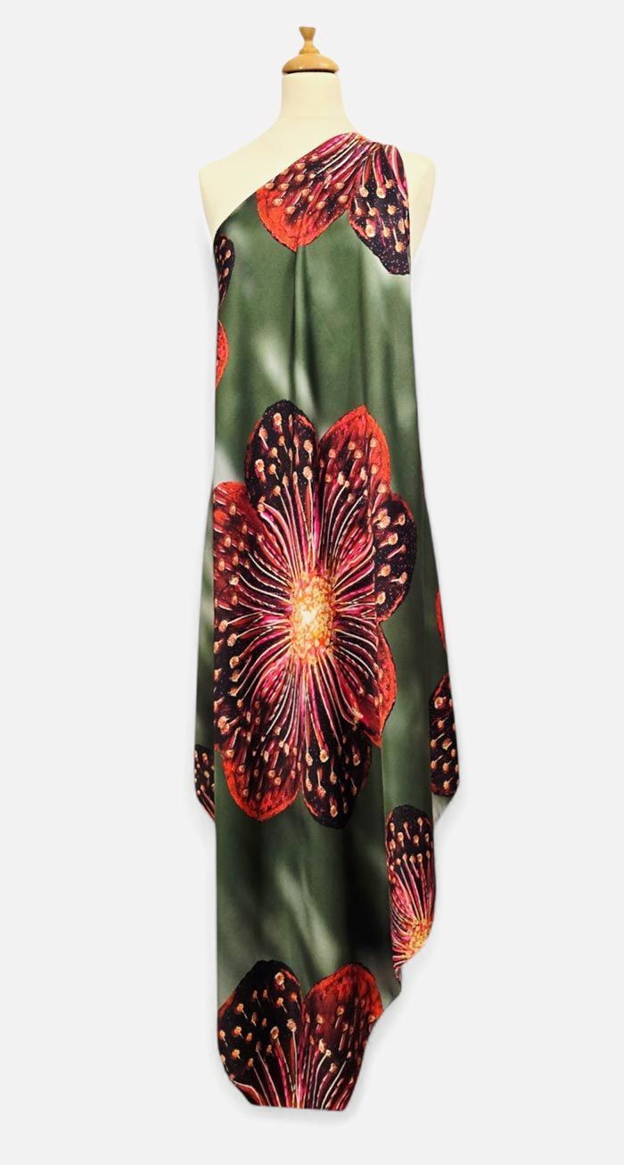 Tela verde con gran estampado floral en tonos rojos y negros sobre un maniquí.