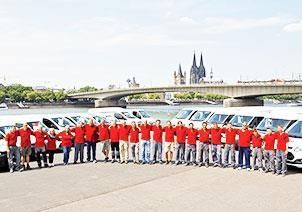 Eine große Gruppe von Menschen posiert vor einem Fluss für ein Foto.