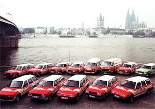 Eine Reihe roter Autos parkt vor einem Gewässer