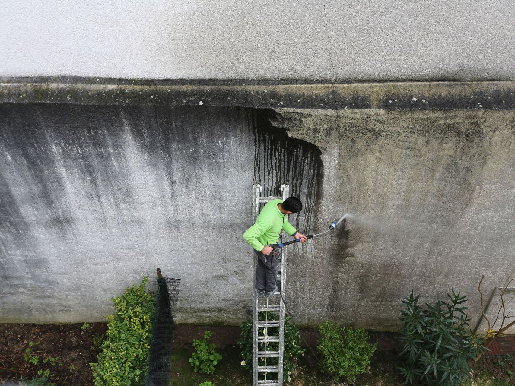 Homme qui nettoie un mur au jet à haute pression