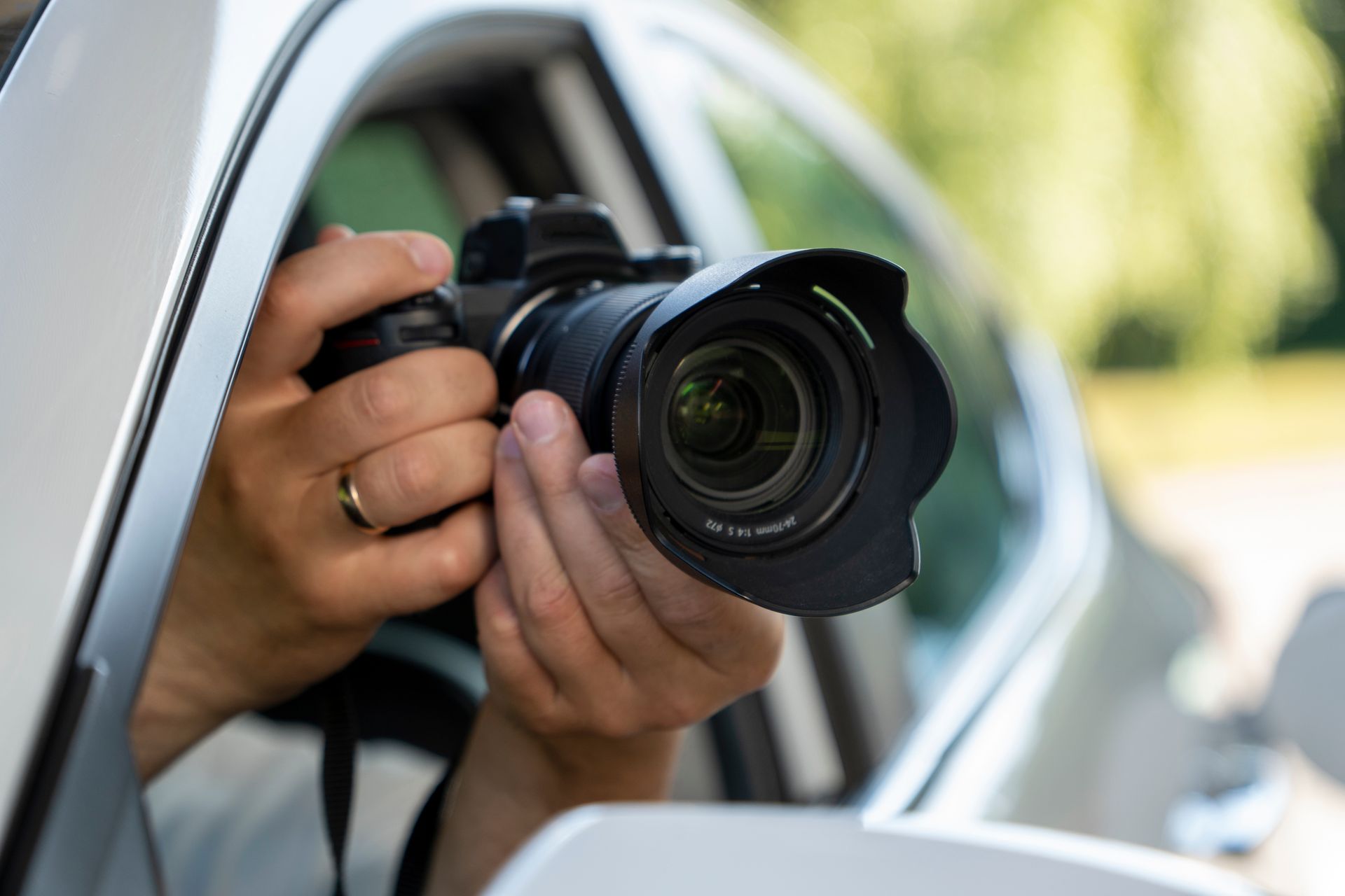 Une personne tient un appareil photo par la fenêtre d'une voiture, pointé vers la route.