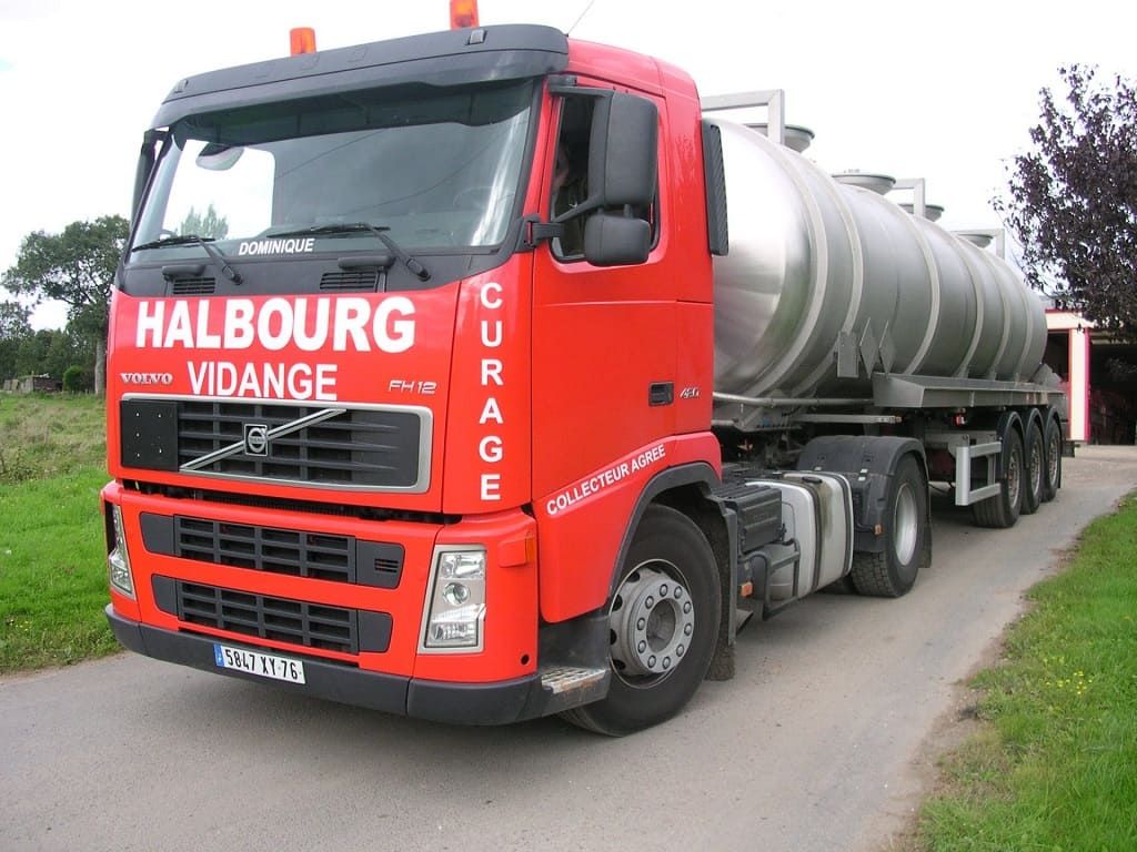 Un camion-citerne Volvo rouge stationné sur une route goudronnée, portant les inscriptions « HALBOURG VIDANGE » et « CURAGE » en lettres blanches.