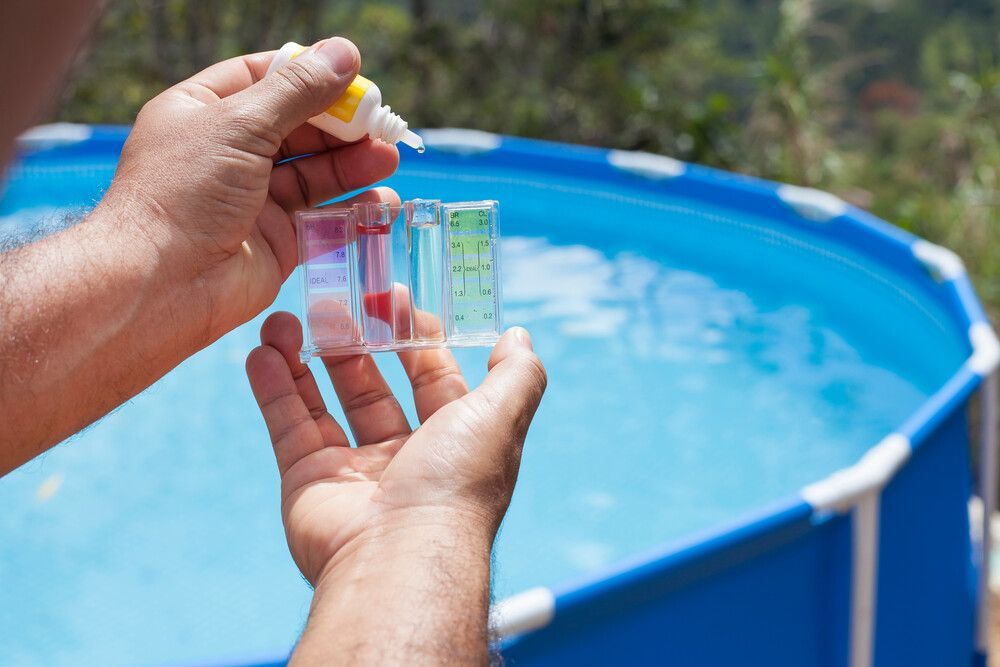 Una persona sostiene un tubo de ensayo frente a una piscina.