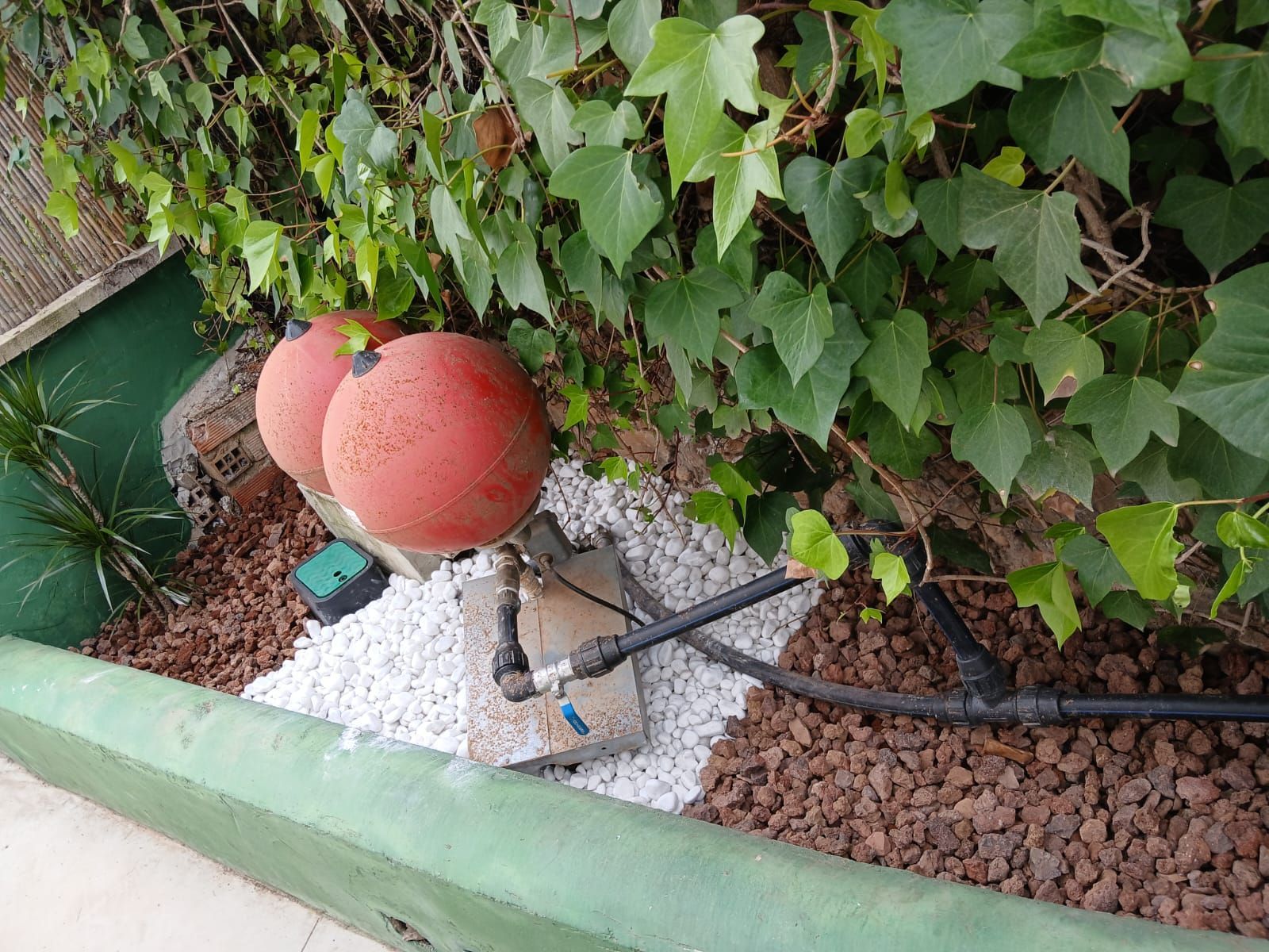 Una jardinera llena de rocas y grava al lado de un arbusto.