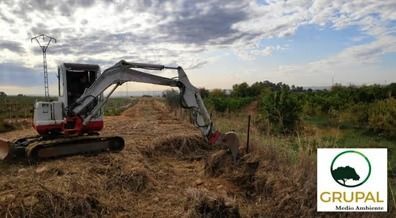 Una pequeña excavadora está cavando un hoyo en un campo.