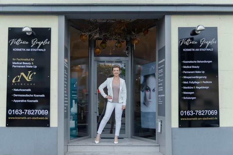 Eine Frau in einem weißen Anzug steht vor einem Geschäft.