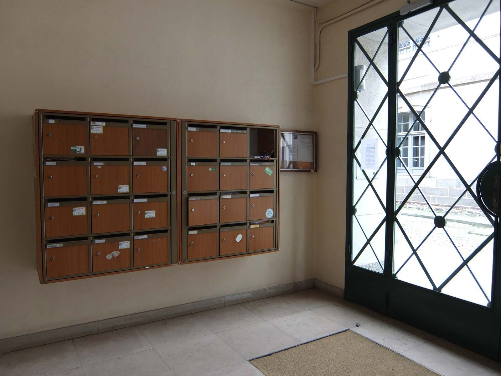 Boîtes aux lettres murales à côté d'une porte vitrée. Boîtes aux lettres en bois brun avec étiquettes.