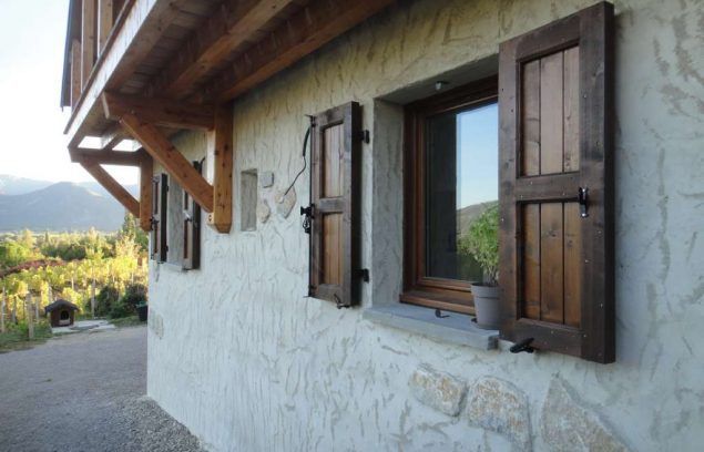 Extérieur d'un bâtiment avec des volets en bois et une façade en pierre.