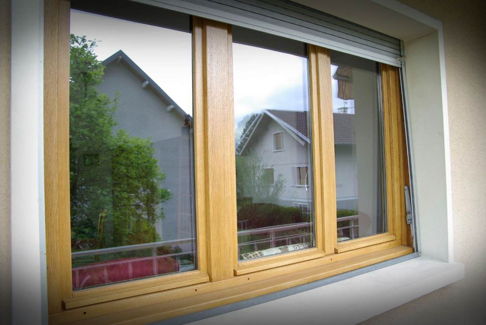 Fenêtre à triple vitrage avec cadre en bois, vue sur les maisons et les arbres, vue extérieure.