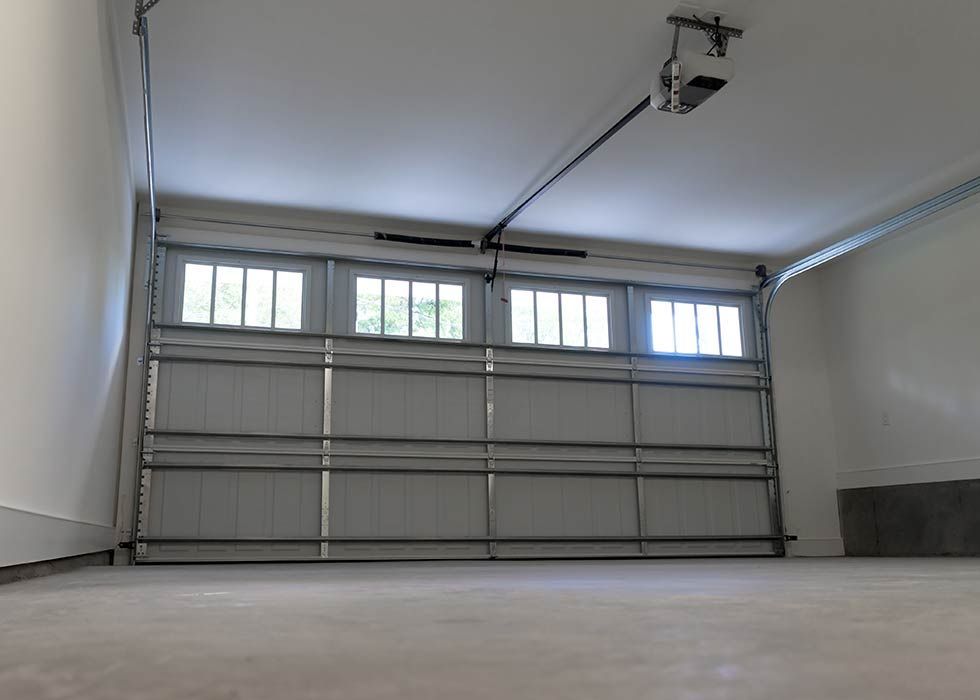 Intérieur d'un garage vide avec une porte de garage fermée de couleur claire et un sol en béton.