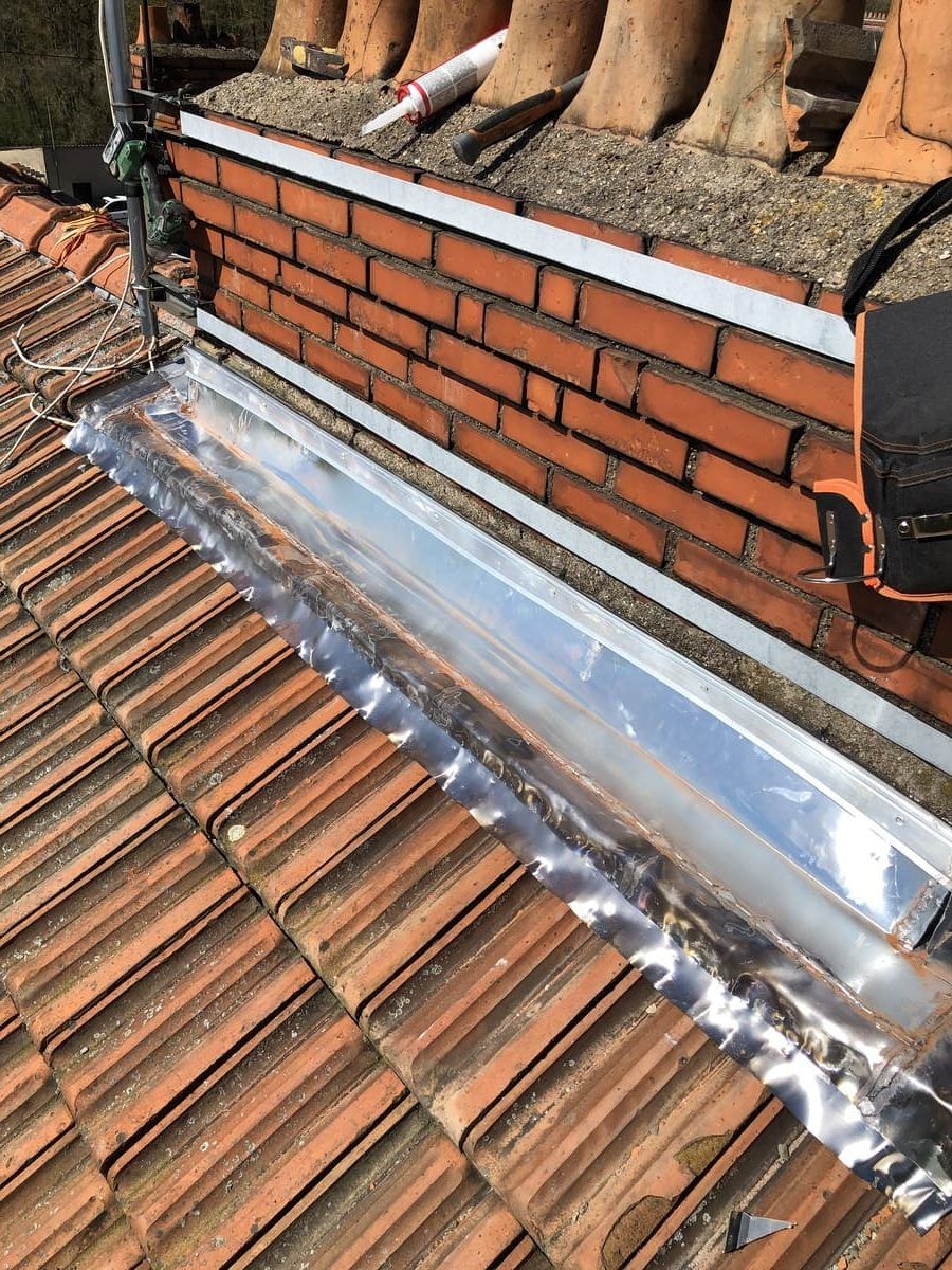 Zinguerie d'un toit sous un mur en brique