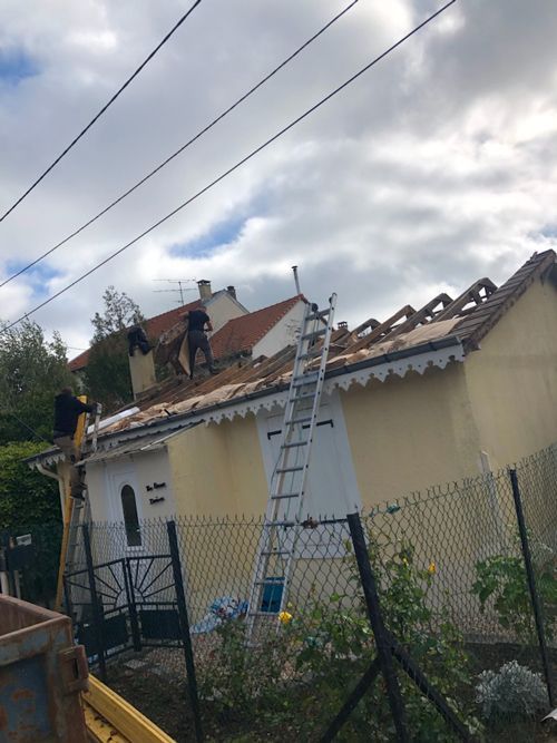 Maison avec façade jaune et échelle menant à un toit en rénovation