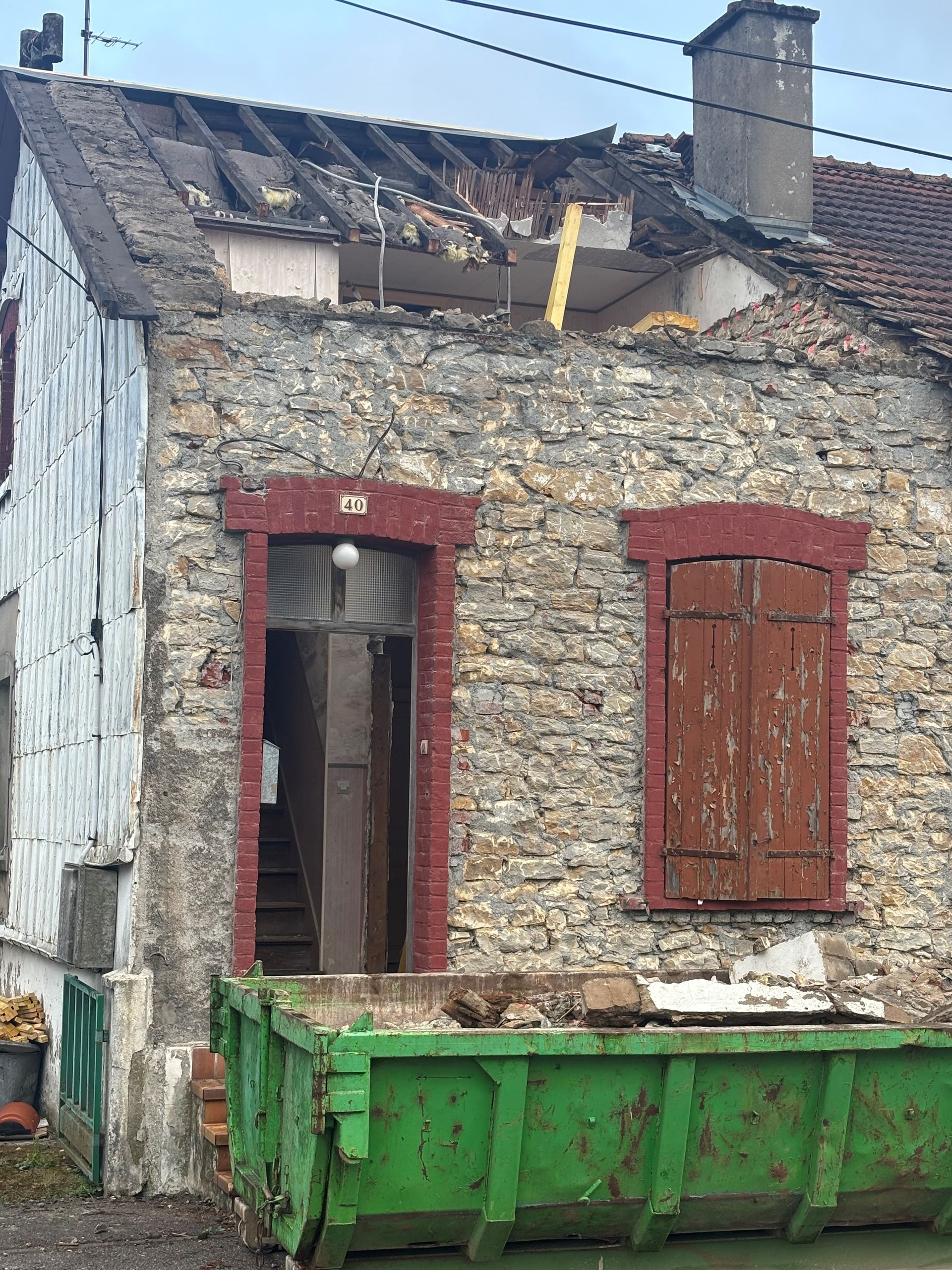 Vieille maison avec bac vert devant