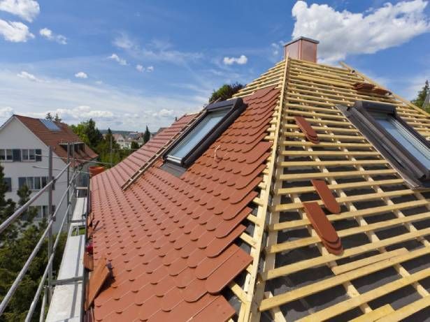 Travaux de rénovation d'une toiture avec la pose de tuiles et de fenêtres de toit