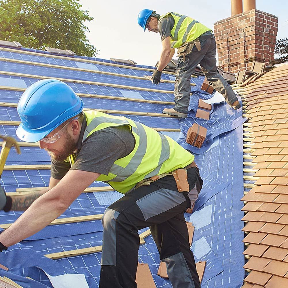Professionnels sur une toiture pour poser une bâche protectrice