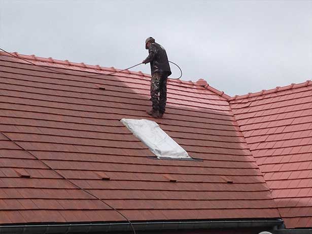 Professionnel en combinaison pour appliquer un traitement sur une toiture
