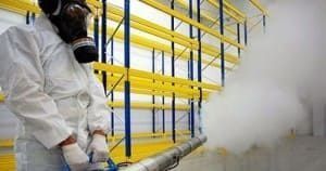 Un hombre que lleva una máscara de gas está rociando una habitación con un nebulizador.