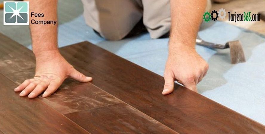 Un hombre está instalando un piso de madera con un martillo.