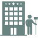 Un hombre está parado frente a un gran edificio sosteniendo un trapeador.