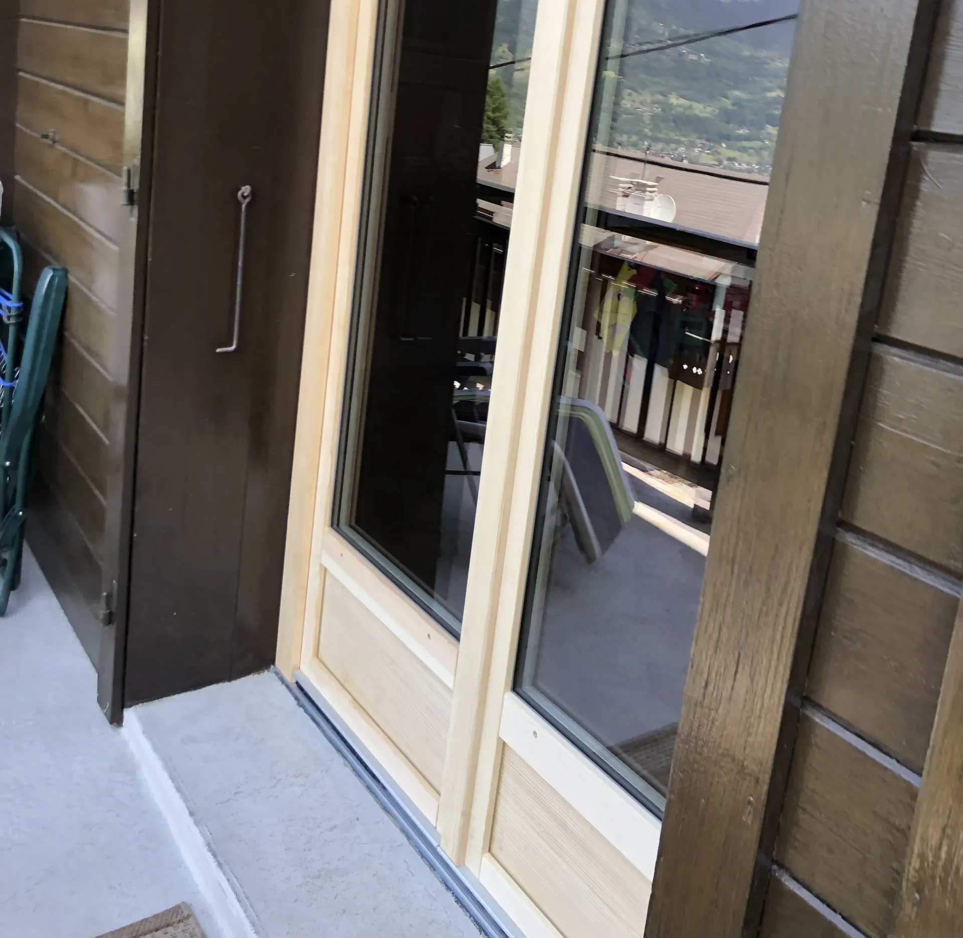 Porte-fenêtre en bois donnant sur une terrasse, double vitrage