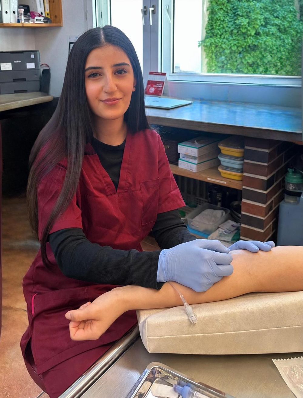 Zahnärztin mit Handschuhen behandelt den Arm eines Patienten in einem Behandlungszimmer
