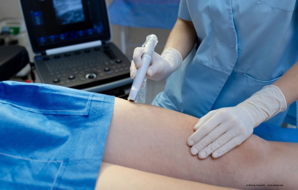Ultraschalluntersuchung des Abdomens eines Patienten, wobei der Arzt Handschuhe und OP-Kleidung trägt.