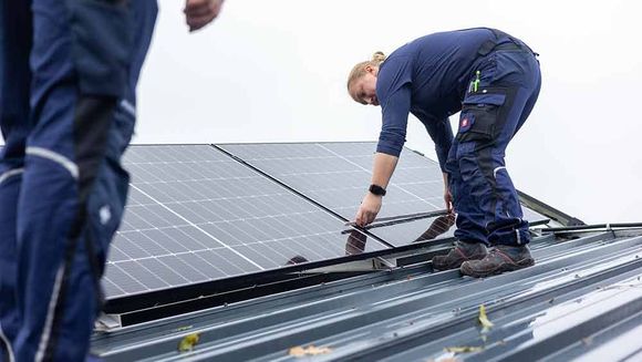 Ein Mann und eine Frau installieren Solarmodule auf einem Dach.