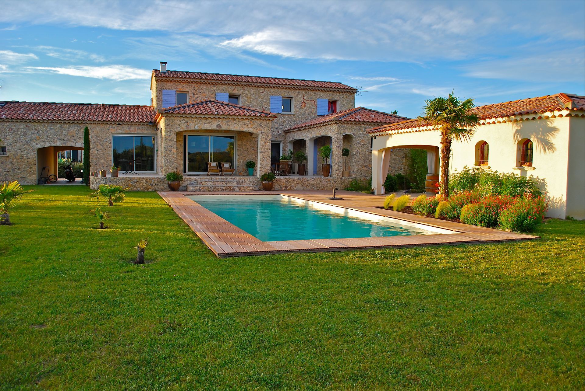 Maison en pierre avec piscine dans un jardin.