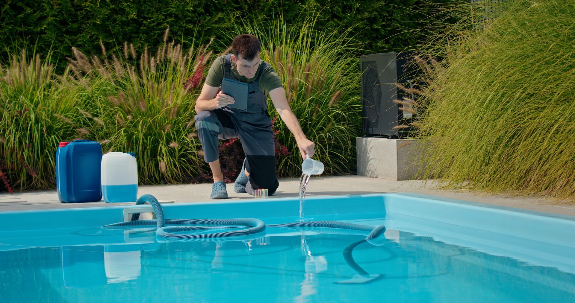 Un homme teste l'eau d'une piscine.