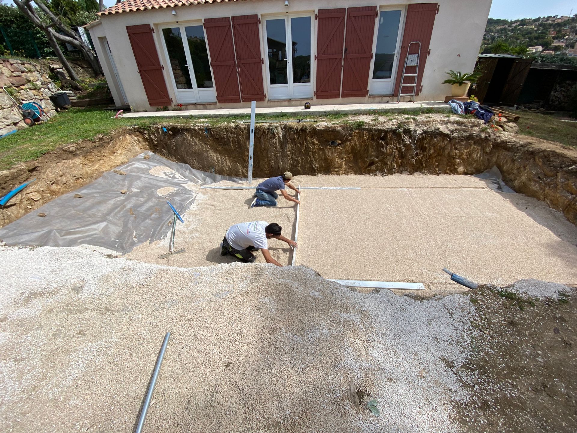 Des techniciens préparent le sol en vue de l'installation de la piscine.