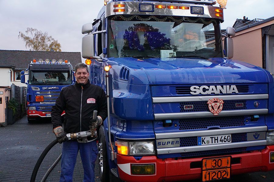 Ein Mann steht vor einem blauen Scania-LKW