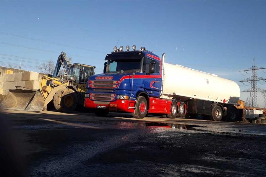 Ein blau-weißer Lastwagen steht auf einem Parkplatz neben einer Planierraupe.