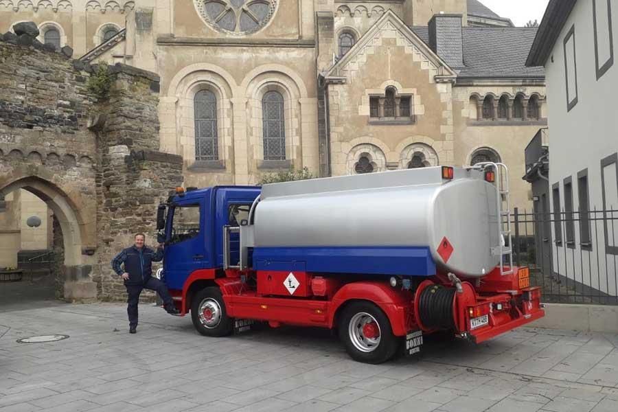 Ein rot-blauer Lastwagen parkt vor einer Kirche.