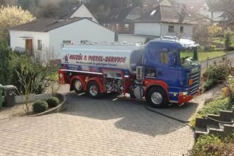 Ein blau-roter Lastwagen steht in der Einfahrt vor einem Haus.