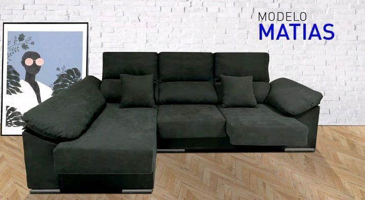 Un sofá negro está sentado frente a una pared de ladrillos blancos.