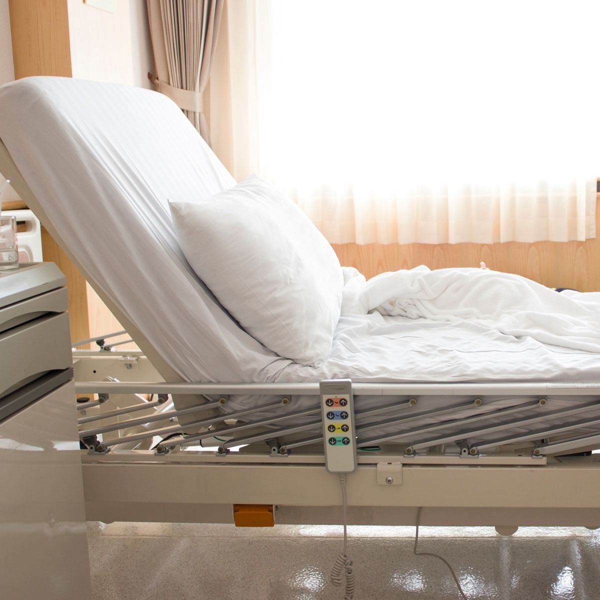 Una cama de hospital con sábanas blancas y un control remoto