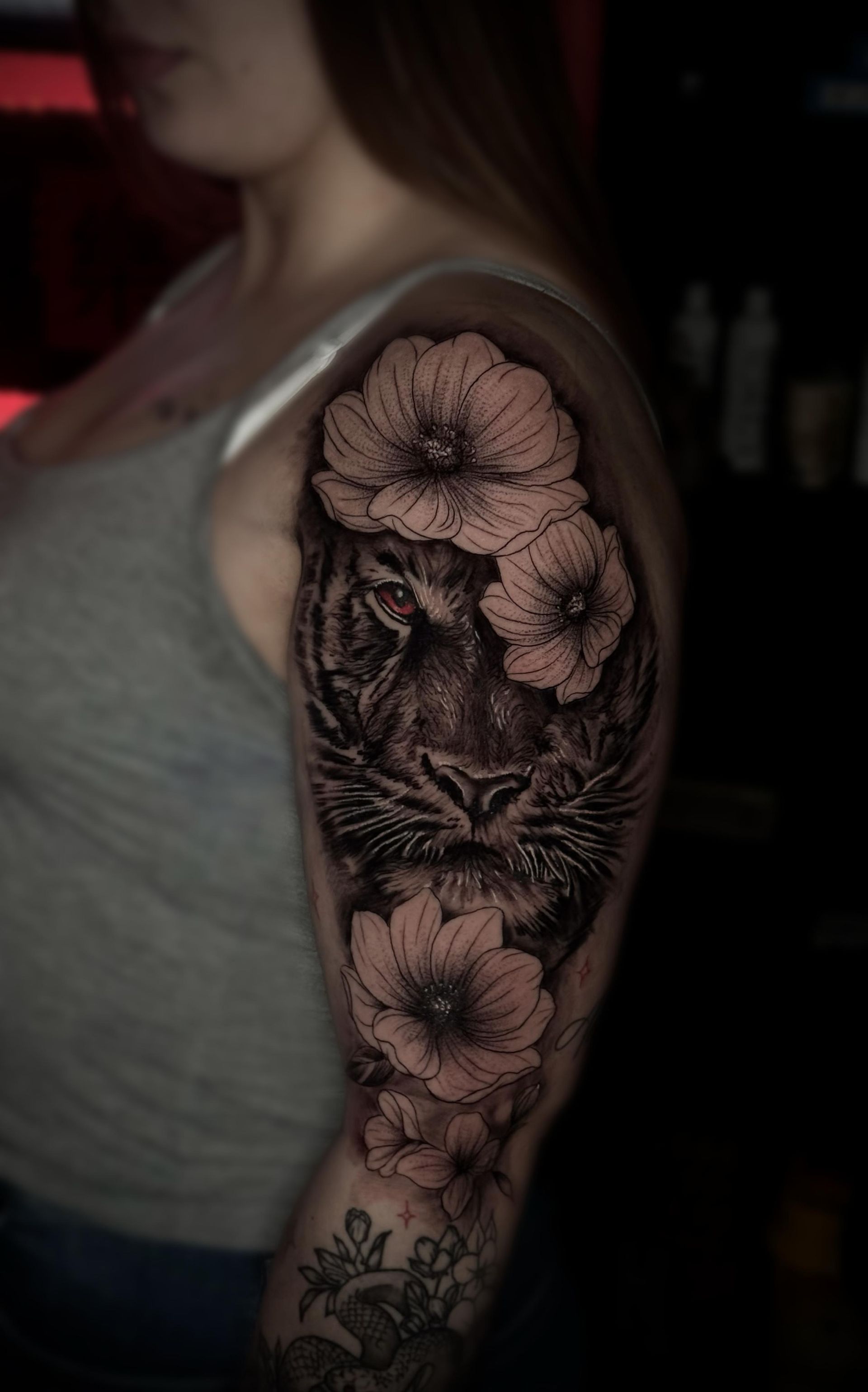 Una mujer tiene un tatuaje de un tigre y flores en su brazo.