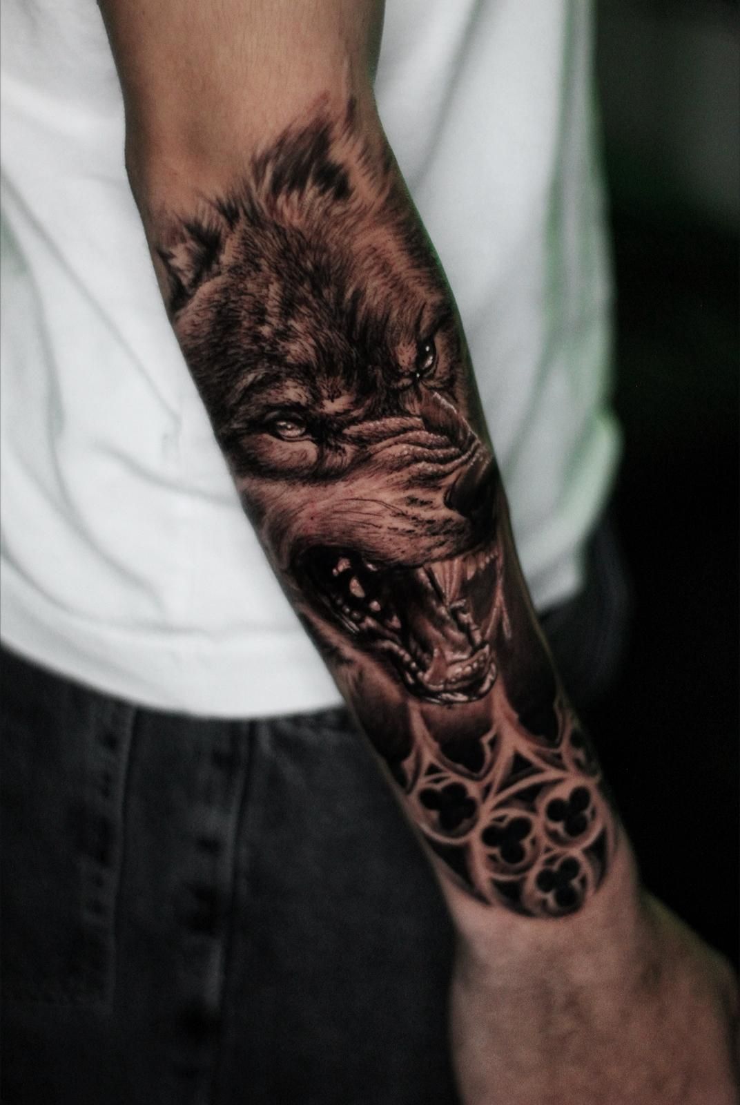 Un hombre tiene un tatuaje de un lobo en su antebrazo.
