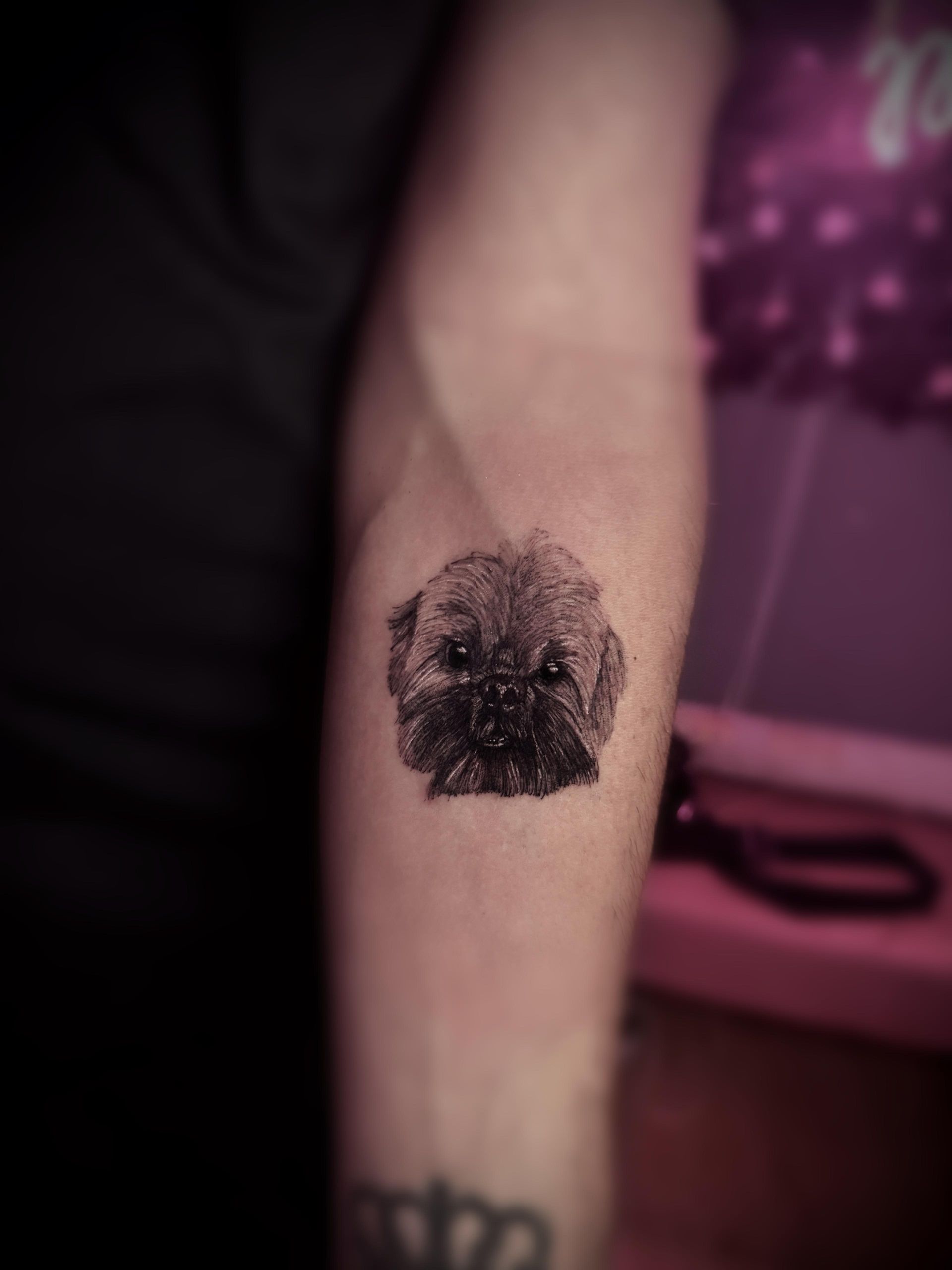 Una persona tiene un tatuaje de un perro en el brazo.