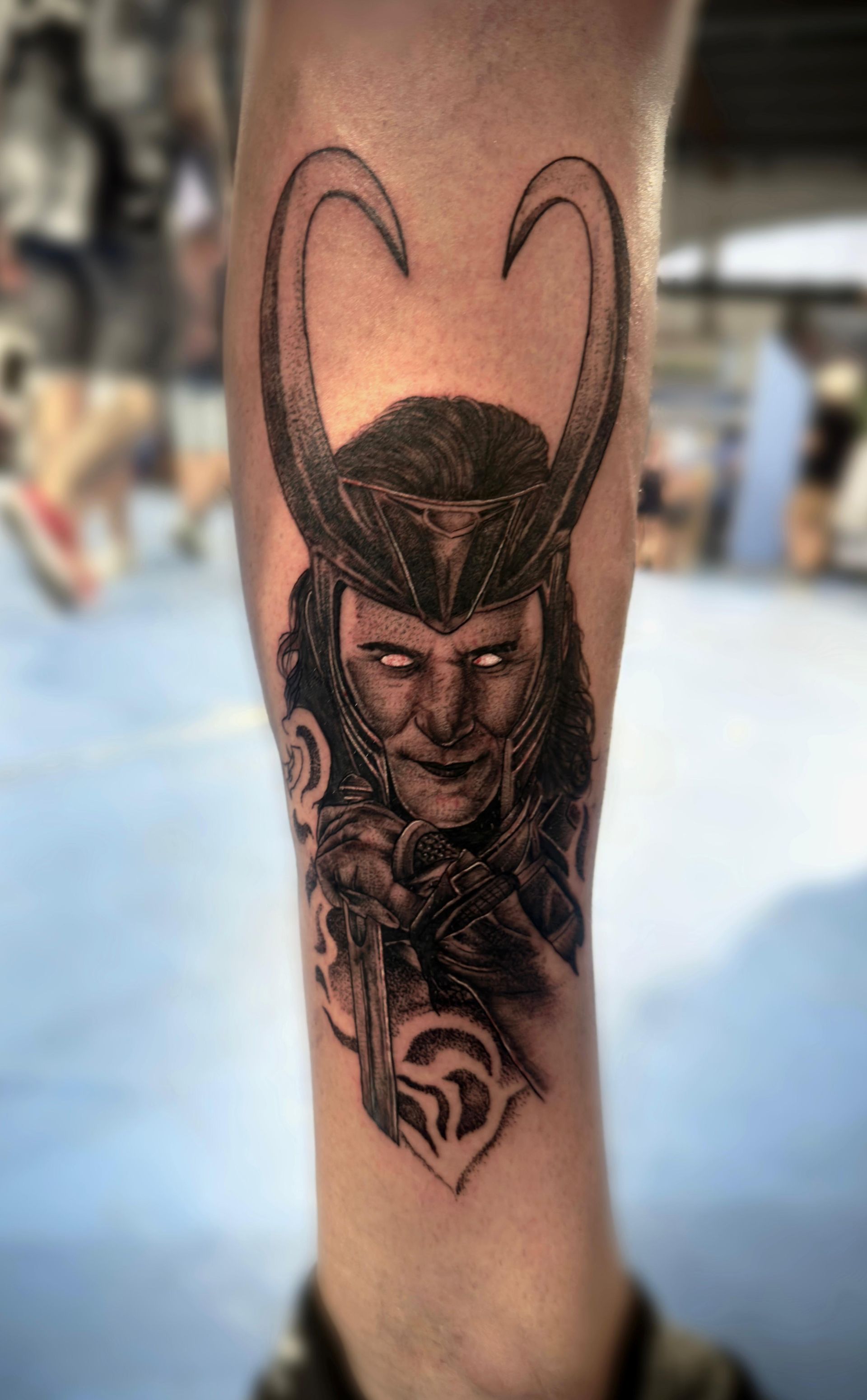 Un tatuaje en blanco y negro de Loki en la pierna de una persona.
