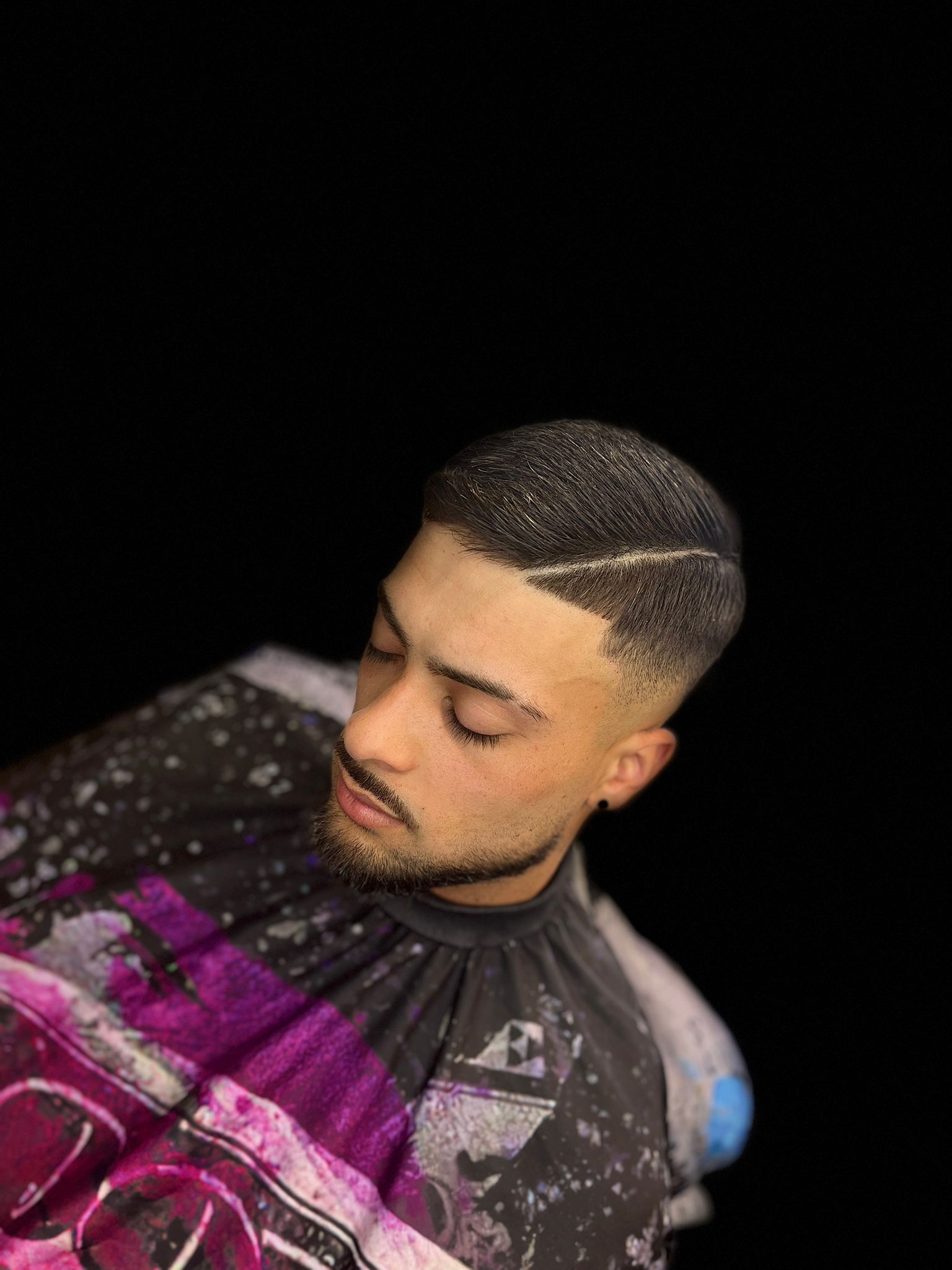 Un hombre con barba se deja cortar el pelo por un barbero.