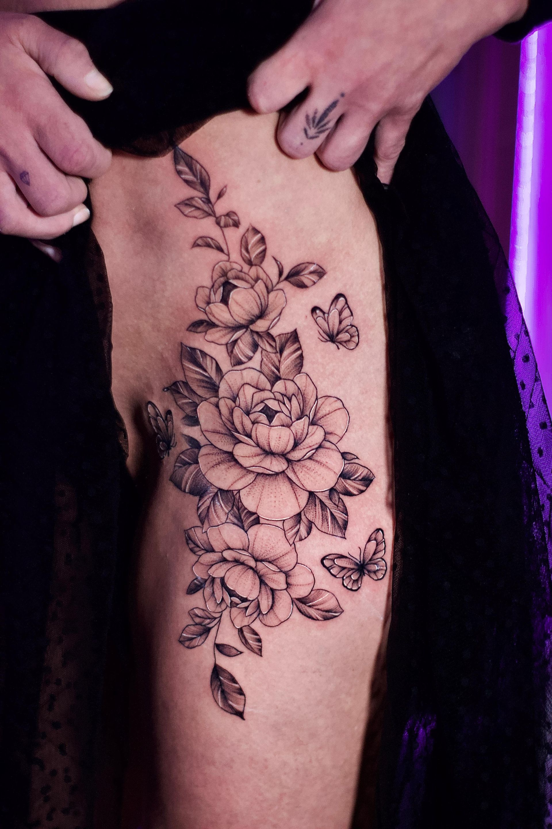 Una mujer tiene un tatuaje de rosas y mariposas en su pierna.