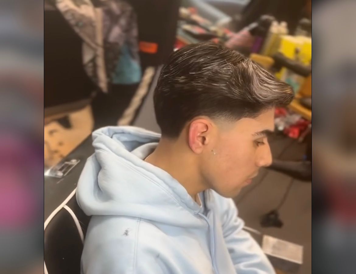 Un joven con una sudadera con capucha azul está sentado en una silla.