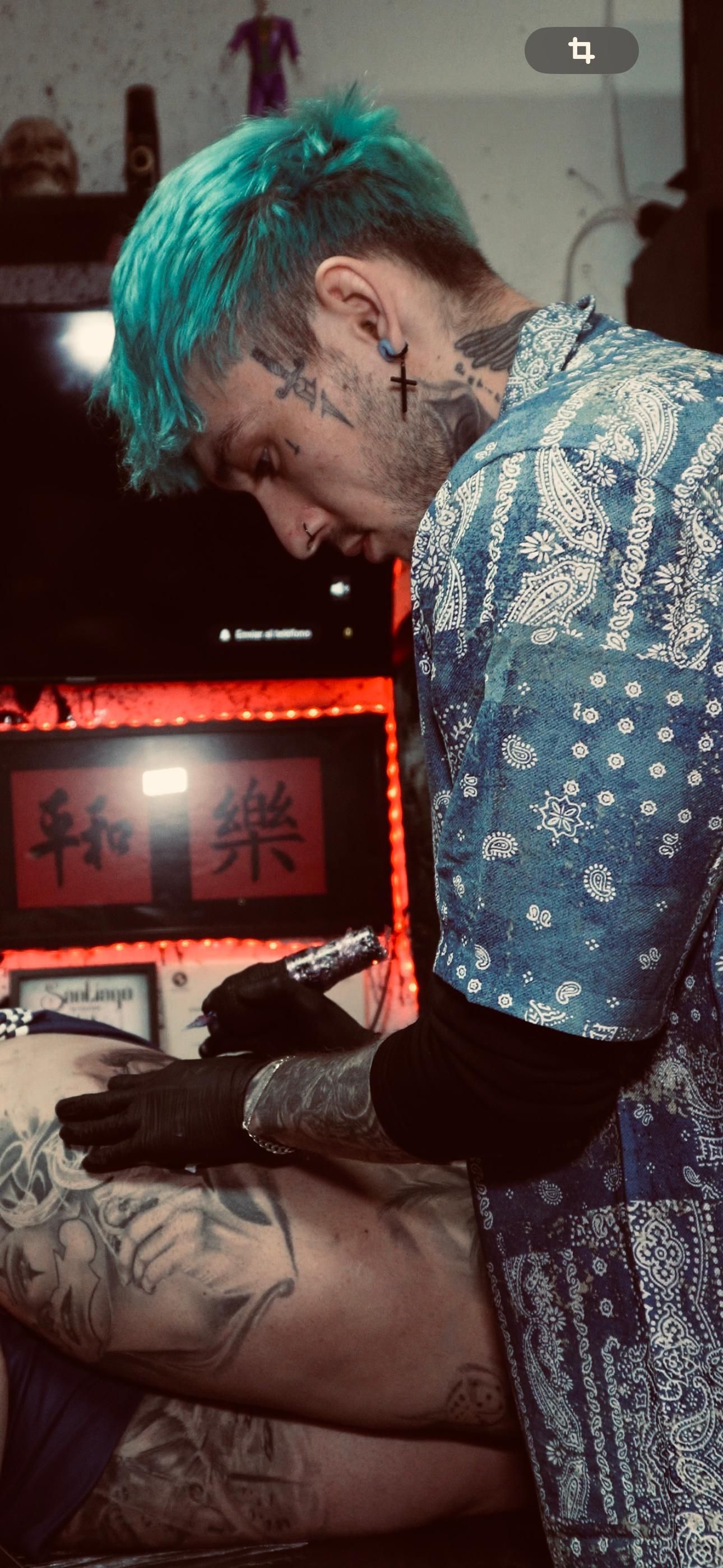 Un hombre con cabello azul se está haciendo un tatuaje en la pierna de una mujer.