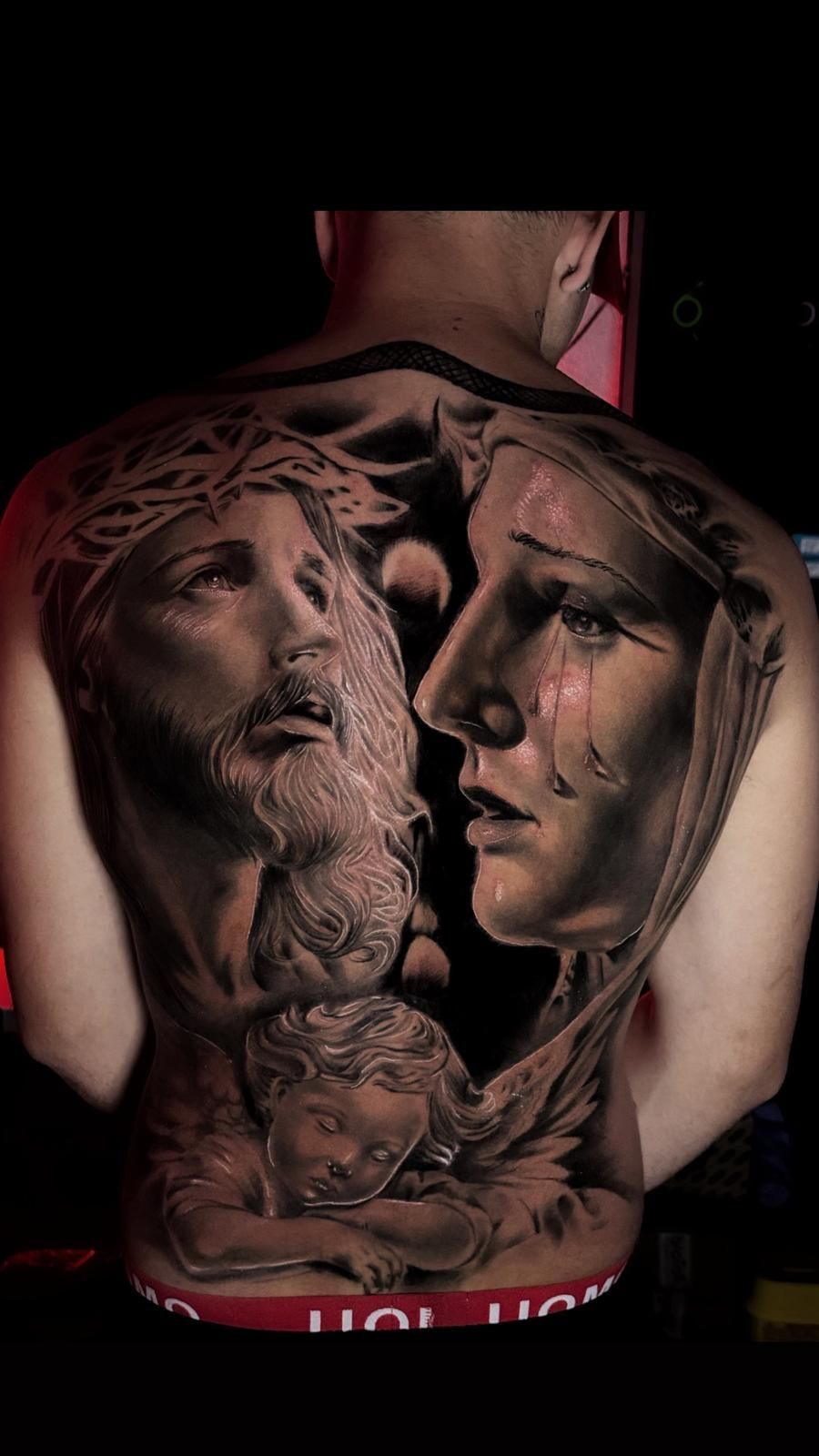 Un hombre tiene un tatuaje de Jesús y María en la espalda.
