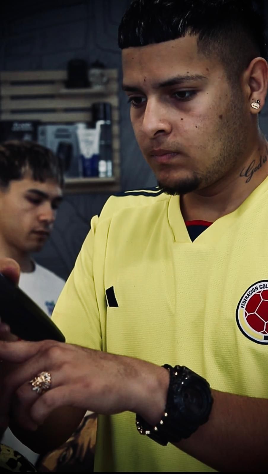 Un hombre con una camisa amarilla está mirando su teléfono.