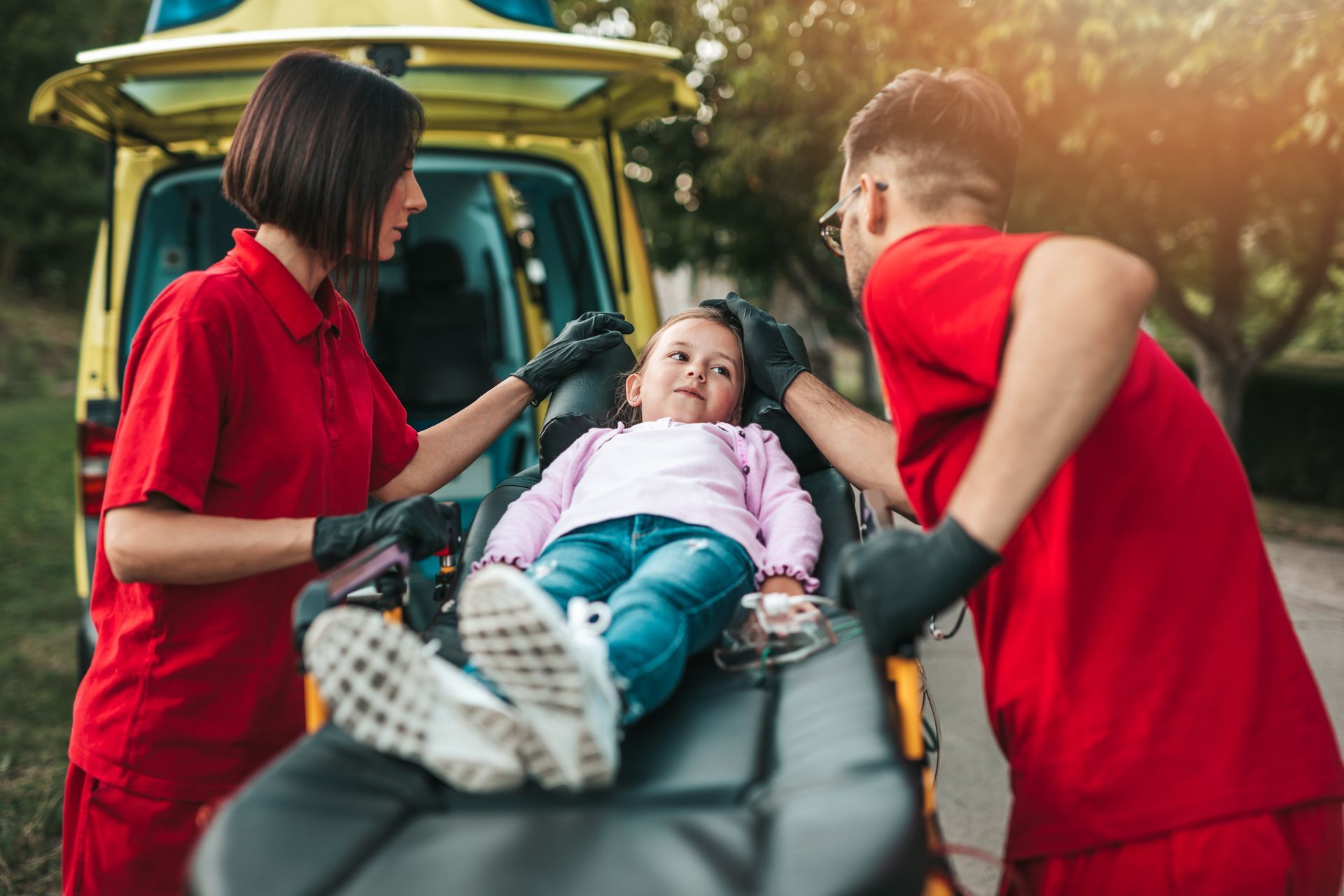 Une enfant entourée de deux ambulanciers avec des t-shirts rouges