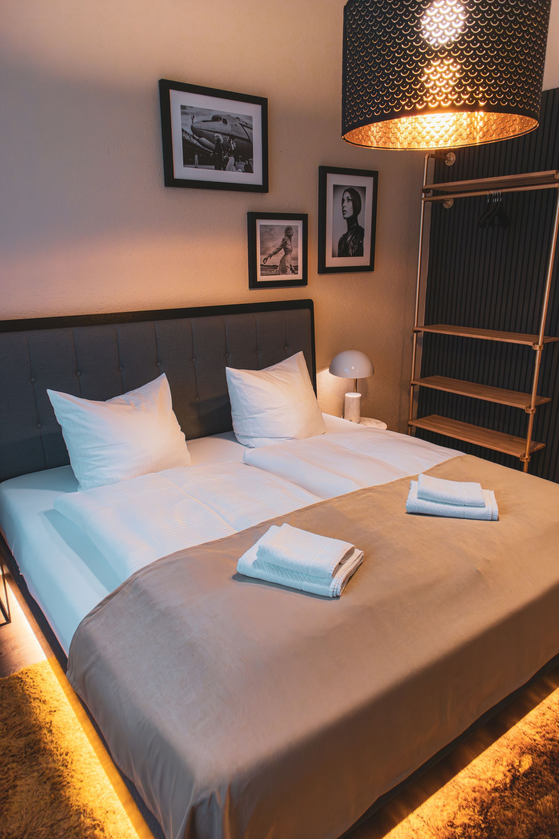 Dekorative schwarze Netzhängelampe neben gerahmten Bildern an einer strukturierten Wand.