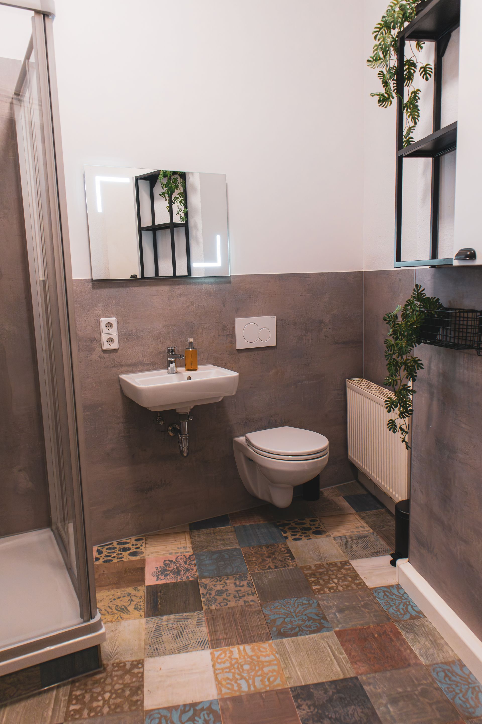 Modernes Doppelbett mit dunklem Kopfteil, Nachttischlampe und gerahmten Bildern an der Wand.